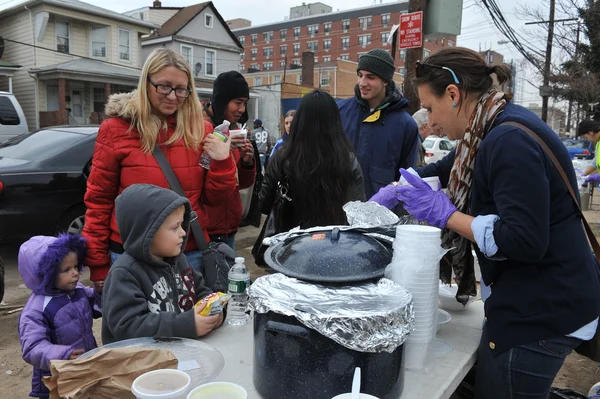 Queens, ny - 11. November: Kinder erhalten Hilfe mit warmen Lebensmitteln, Kleidung und Vorräten im Strandbereich von Rockaway Beach aufgrund der Auswirkungen des Hurrikans "Sandy" in Queens, New York, USA, am 11. November 2012. — Stockfoto