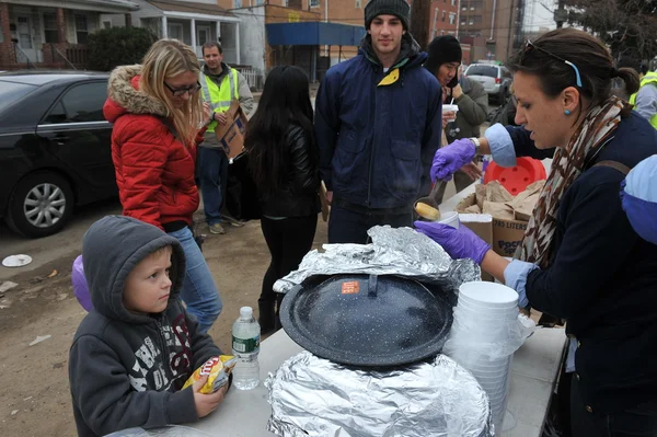 QUEENS, NY - 11 DE NOVIEMBRE: Niños recibiendo ayuda con comida caliente, ropa y suministros en el área de la playa Rockaway debido al impacto del huracán Sandy en Queens, Nueva York, Estados Unidos, el 11 de noviembre de 2012 . — Foto de Stock