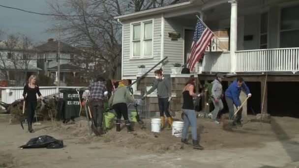 Queens, ny - 11 november: een vrijwilligers het zand in de woonwijk van rockaway beach schoonmaken na orkaan zandstrand in queens, new york, VS, op 11 november 2012. — Stockvideo