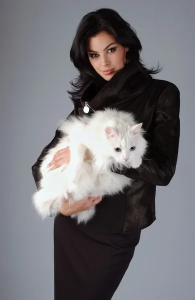 Porträtt av sofistikerad brunett kvinna anläggning vit katt — Stockfoto