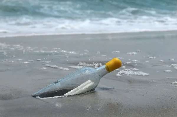 Послание в бутылке на песке и океане на фоне — стоковое фото