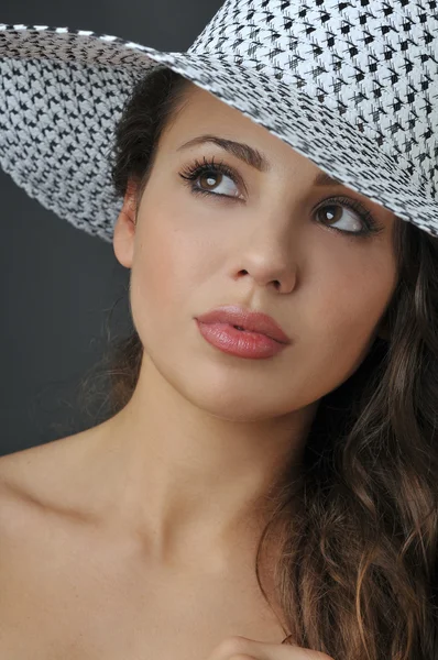 Güzel genç esmer kız çok beyaz elbise ve şapka giyen Studio kamera için poz — Stok fotoğraf