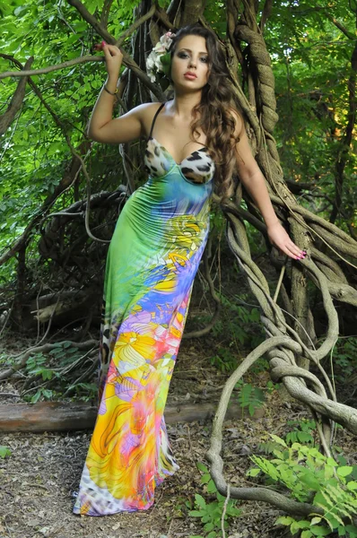 Όμορφη μελαχρινή μοντέλο που θέτουν αρκετά σε τροπική ζούγκλα, φορώντας το πολύχρωμο φόρεμα σχεδιαστές — Φωτογραφία Αρχείου