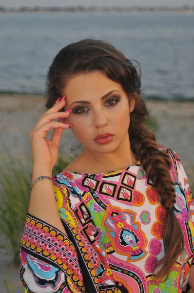 Hermosa modelo morena posando bastante en la playa tropical vistiendo cortos diseñadores vestido colorido — Foto de Stock