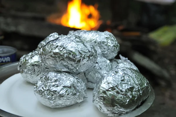 Hacer papas en papel de aluminio sobre la chimenea en el camping — Foto de Stock