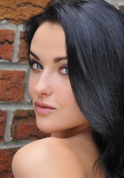 Attractive smiling young woman looking over the shoulder. Shallow depth of field, focus on eyes. — Stock Photo, Image