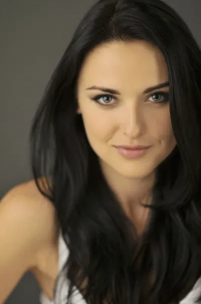 Attractive smiling young brunette woman with blue eyes. Shallow depth of field, focus on eyes. — Stock Photo, Image