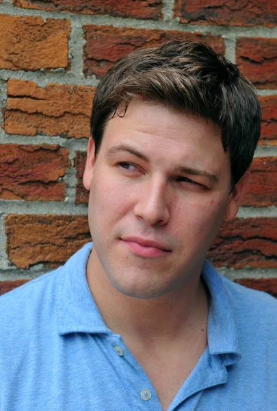 Jeune acteur masculin faisant expression faciale émotionnelle devant la caméra avec fond de mur de briques — Photo