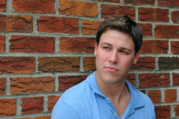 Joven actor masculino haciendo expresión facial emocional delante de la cámara con fondo de pared de ladrillo — Foto de Stock