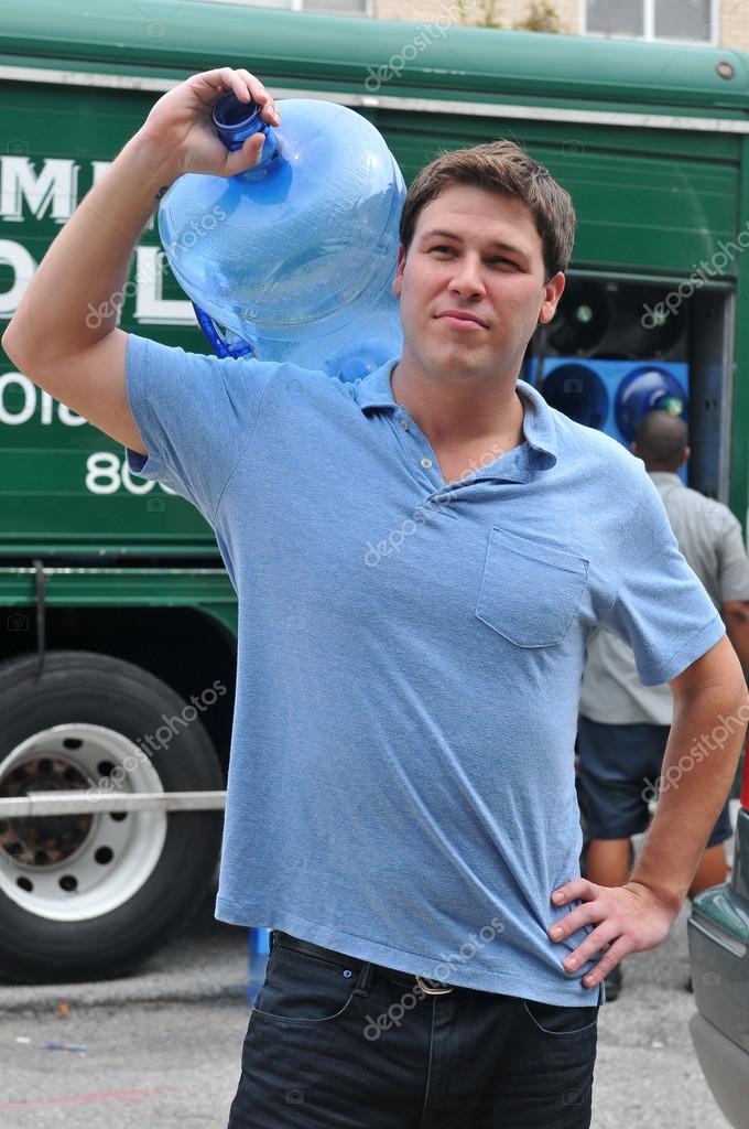 Friendly delivery man bringing 5 gallon water jugs — Stock Photo