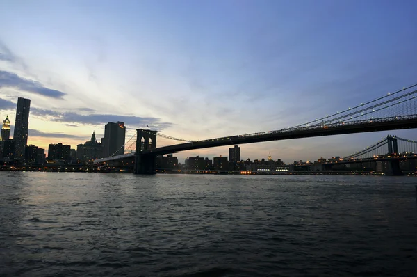 Ciudad de Nueva York horizonte de la noche con el puente de Brooklyn sobre el río Hudson — Foto de Stock