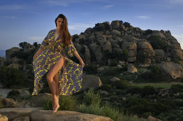 An attractive young woman wearing a designe's bikini and beach dress stands in front of a rock. Stony Point park, Topanga Canyon Blvd, Chatsworth, CA