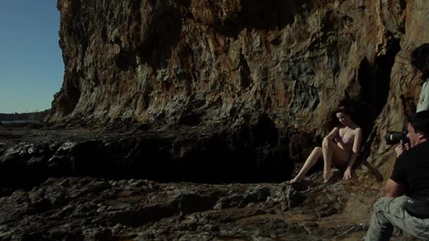 Morena modelo posando no fundo de lava rochosa com respingo de onda no fundo — Vídeo de Stock