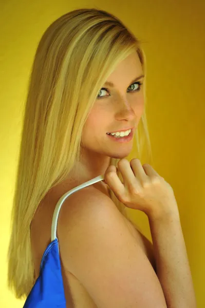 Blond flicka poserar sexigt framför gula väggen — Stockfoto