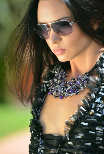 Модна модель в сонцезахисних окулярах і намистах з дорогоцінними каменями — стокове фото