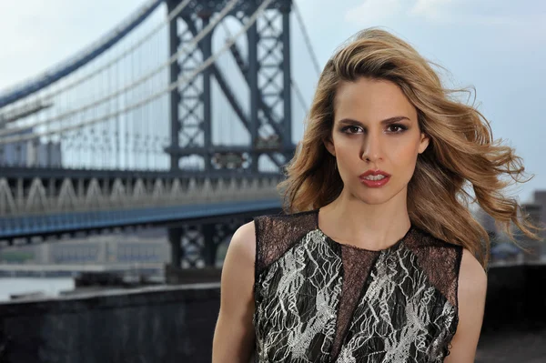 Primer plano retrato de modelo de moda con el pelo sexy completo y labios rojos posando en la ubicación de la azotea con la construcción de puente de metal en el fondo —  Fotos de Stock