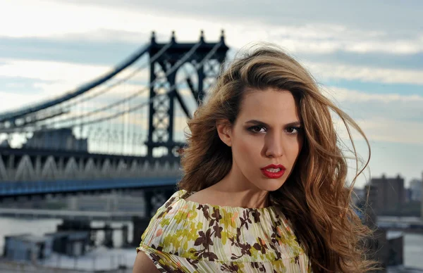 Primer plano retrato de modelo de moda con el pelo sexy completo y labios rojos posando en la ubicación de la azotea con la construcción de puente de metal en el fondo —  Fotos de Stock