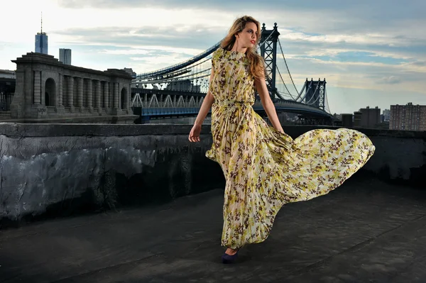 セクシー、身に着けている長いイブニング ドレス屋上上金属橋建設の背景にポーズをとってファッション モデル — ストック写真