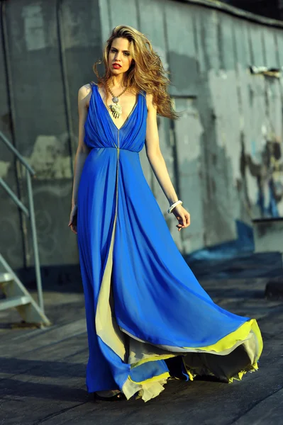 Fashion model posing sexy, wearing long blue evening dress on rooftop location — Stock Photo, Image