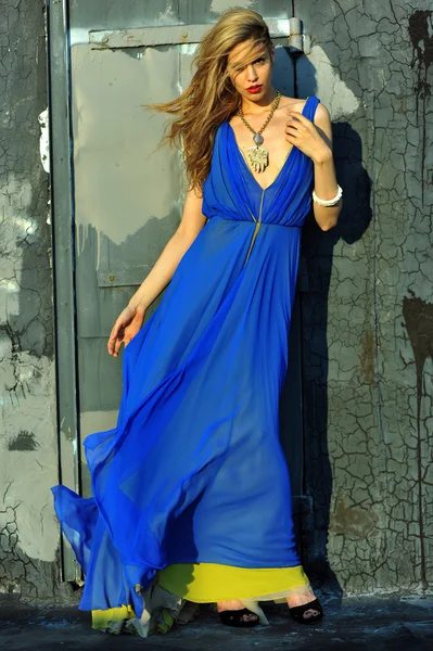 Fashion model posing sexy, wearing long blue evening dress on rooftop location — Stock Photo, Image