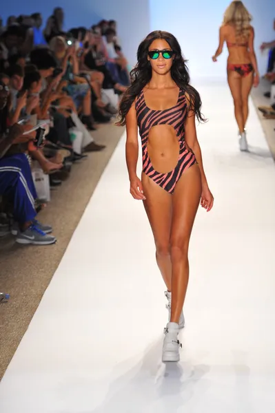 En modell går banan vid stranden riot swimwear showen — Stockfoto