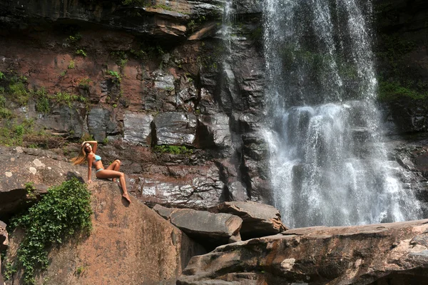 Beautiful slim fitness model posing sexy in front of waterfalls — Stock Photo, Image