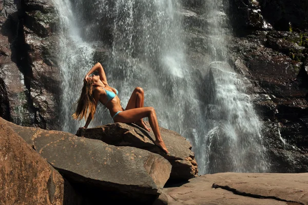 Красивая стройная модель фитнеса позирует сексуально перед водопадами — стоковое фото
