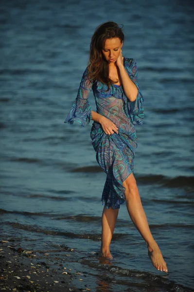 Vrouw die zich voordeed op het strand in jurk — Stockfoto