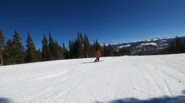 Kırmızı ceketli kayakçı Breckenridge Kayak Merkezi Colorado 'da yüksek hızda yokuş aşağı gidiyor..