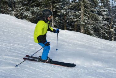 Man skier in bright outfit skiing downhill at the Stowe Mountain Resort. 