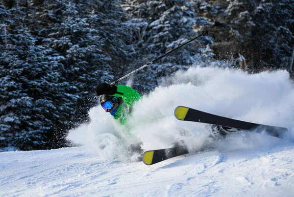 新鮮なパウダースノーで明るい衣装の男性スキーヤーが下り坂で滑ります — ストック写真