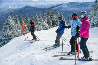 Skiers getting ready downhill at Peak Mansfield at Stowe Mountain Resort, Vermont. Diamond ski trail.