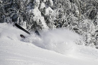 Skier falling on the slope on fresh powder snow at winter resort.