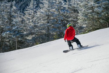 Dynamic photo of snowboarder in bright jacket downhill. Enjoying winter vacation snowboarding in the mountains on fresh powder snow slopes.