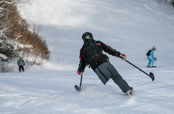 Adaptive Skiing with one leg : Disabled ski racer a three-tracker, or one-legged skier training kids how to ski at Stowe mountain resort