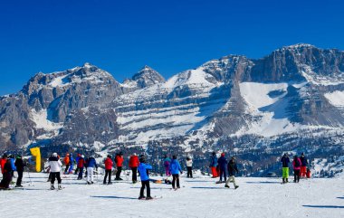 Kayakçılar ve snowboardcular, İtalya, Avrupa 'daki Brenta Dolomitleri bölgesinde yer alan Madonna di Campiglio Kayak Merkezinde güneşli güzel bir günün tadını çıkarıyorlar..