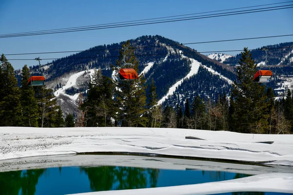 犹他州公园城峡谷滑雪区橙色泡泡椅电梯 晚春气候条件 观赏有滑雪场和池塘的高山 — 图库照片