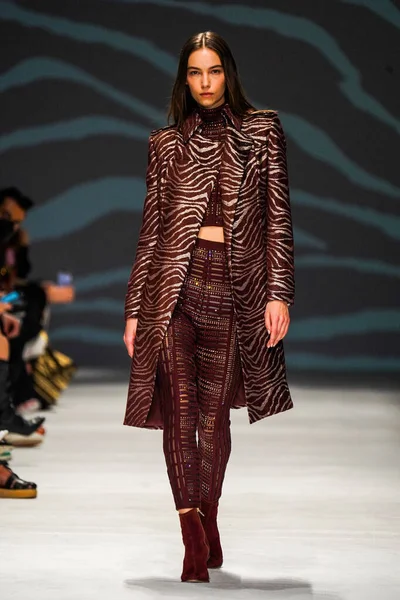 MİLAN, İTALYA - 24 Şubat 2022 'de Milano Moda Haftası / Kış 2023' te İtalya 'nın Milano kentinde düzenlenen Genny defilesinde bir model podyumda yürüyor..