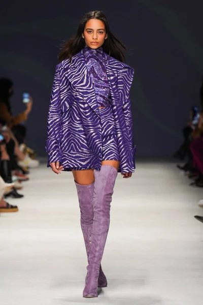 MİLAN, İTALYA - 24 Şubat 2022 'de Milano Moda Haftası / Kış 2023' te İtalya 'nın Milano kentinde düzenlenen Genny defilesinde bir model podyumda yürüyor..