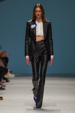 MİLAN, İTALYA - 24 Şubat 2022 'de Milano Moda Haftası / Kış 2023' te İtalya 'nın Milano kentinde düzenlenen Genny defilesinde bir model podyumda yürüyor..