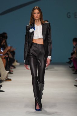 MİLAN, İTALYA - 24 Şubat 2022 'de Milano Moda Haftası / Kış 2023' te İtalya 'nın Milano kentinde düzenlenen Genny defilesinde bir model podyumda yürüyor..