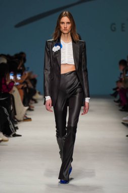 MİLAN, İTALYA - 24 Şubat 2022 'de Milano Moda Haftası / Kış 2023' te İtalya 'nın Milano kentinde düzenlenen Genny defilesinde bir model podyumda yürüyor..