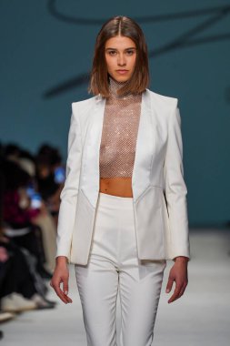 MİLAN, İTALYA - 24 Şubat 2022 'de Milano Moda Haftası / Kış 2023' te İtalya 'nın Milano kentinde düzenlenen Genny defilesinde bir model podyumda yürüyor..