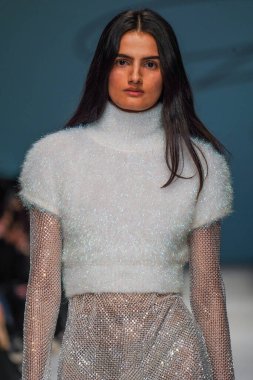 MİLAN, İTALYA - 24 Şubat 2022 'de Milano Moda Haftası / Kış 2023' te İtalya 'nın Milano kentinde düzenlenen Genny defilesinde bir model podyumda yürüyor..