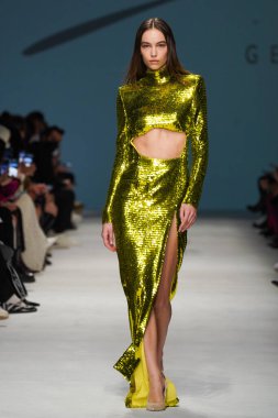 MİLAN, İTALYA - 24 Şubat 2022 'de Milano Moda Haftası / Kış 2023' te İtalya 'nın Milano kentinde düzenlenen Genny defilesinde bir model podyumda yürüyor..