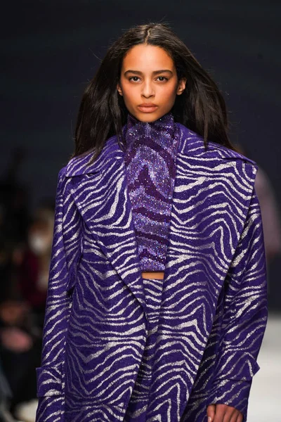 MİLAN, İTALYA - 24 Şubat 2022 'de Milano Moda Haftası / Kış 2023' te İtalya 'nın Milano kentinde düzenlenen Genny defilesinde bir model podyumda yürüyor..