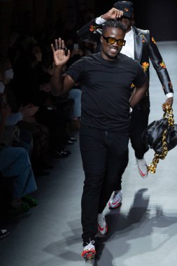 MILAN, İtalya - 26 Şubat 2022 tarihinde Milano, İtalya 'da düzenlenen Milan Moda Haftası / Kış 2023 sırasında Tokyo James defilesinde tasarımcı ve model podyum finalinde yürür..