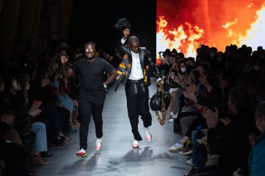 MILAN, İtalya - 26 Şubat 2022 tarihinde Milano, İtalya 'da düzenlenen Milan Moda Haftası / Kış 2023 sırasında Tokyo James defilesinde tasarımcı ve model podyum finalinde yürür..