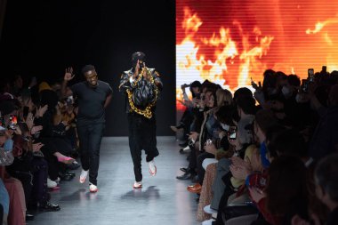 MILAN, İtalya - 26 Şubat 2022 tarihinde Milano, İtalya 'da düzenlenen Milan Moda Haftası / Kış 2023 sırasında Tokyo James defilesinde tasarımcı ve model podyum finalinde yürür..