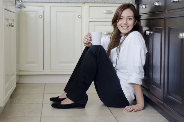 Ung kvinna dricker kaffe sitter på golvet — Stockfoto